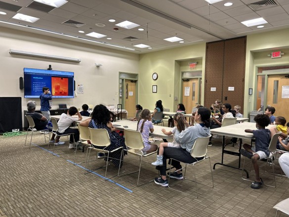 Children seated in a library meeting room during a pottery science session